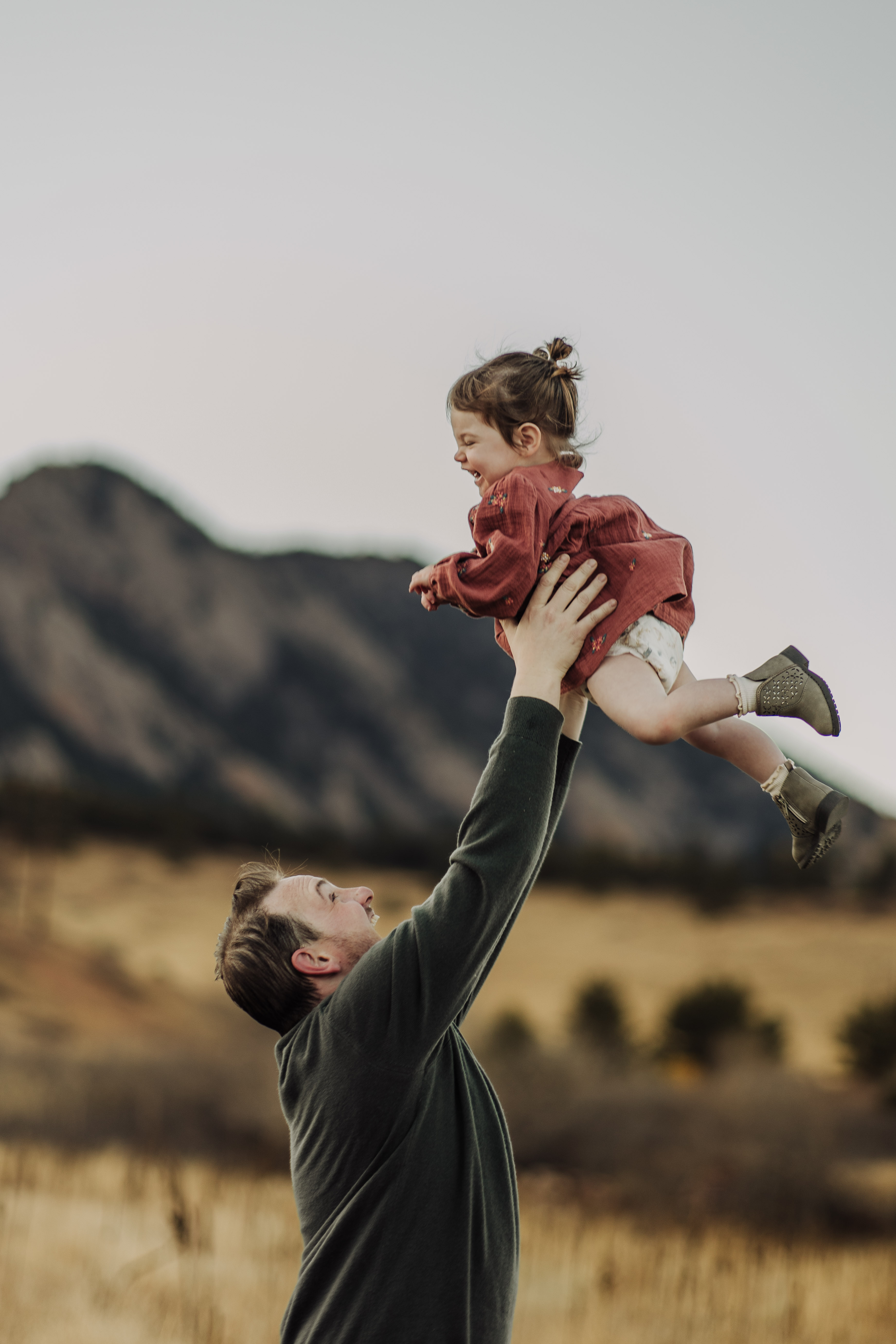 Chris lifting Sloane in the air with the Flatirons behind them